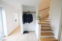 Diele, Nische für Garderobe, Betontreppe mit Holzbelag und Abstellraum unter der Treppe
